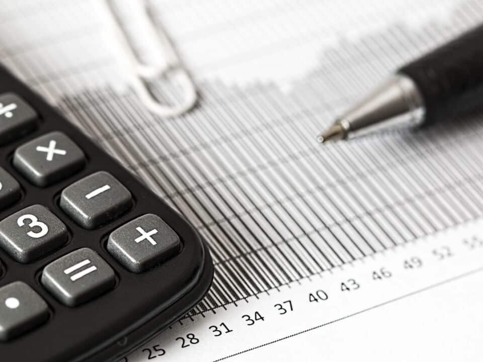 Imagem de um documento, uma caneta e uma calculadora.