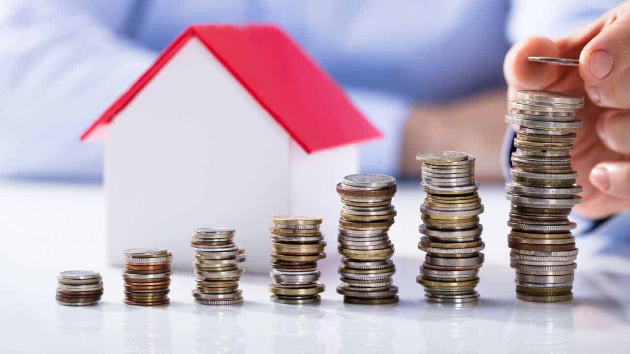 Imagem de miniatura de casa com moedas empilhadas em formato de gráfico