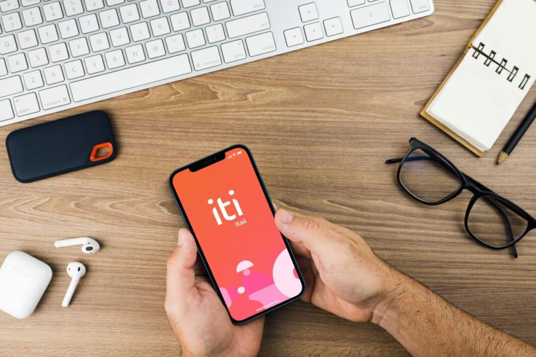 Mãos masculinas segurando celular com que mostra a tela inicial do app Iti Itaú