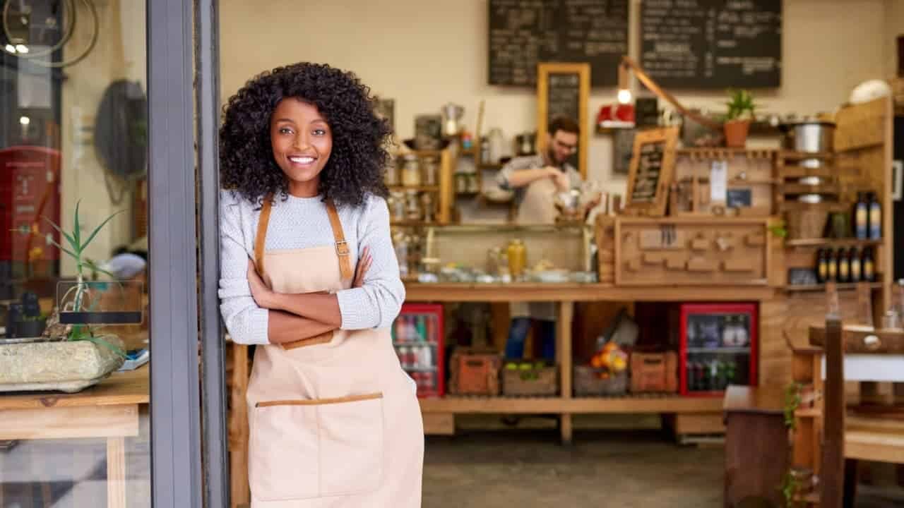 Uma empreendedora sorrindo em frente a uma loja