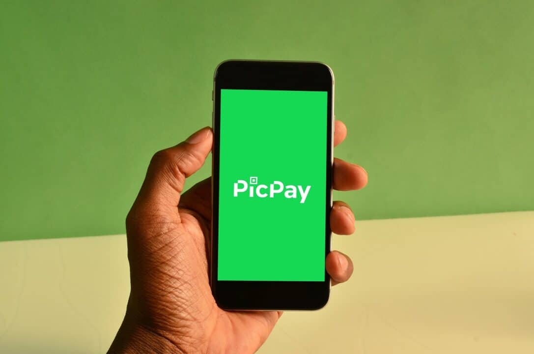 Mão segurando um smartphone com a logo do PicPay na tela