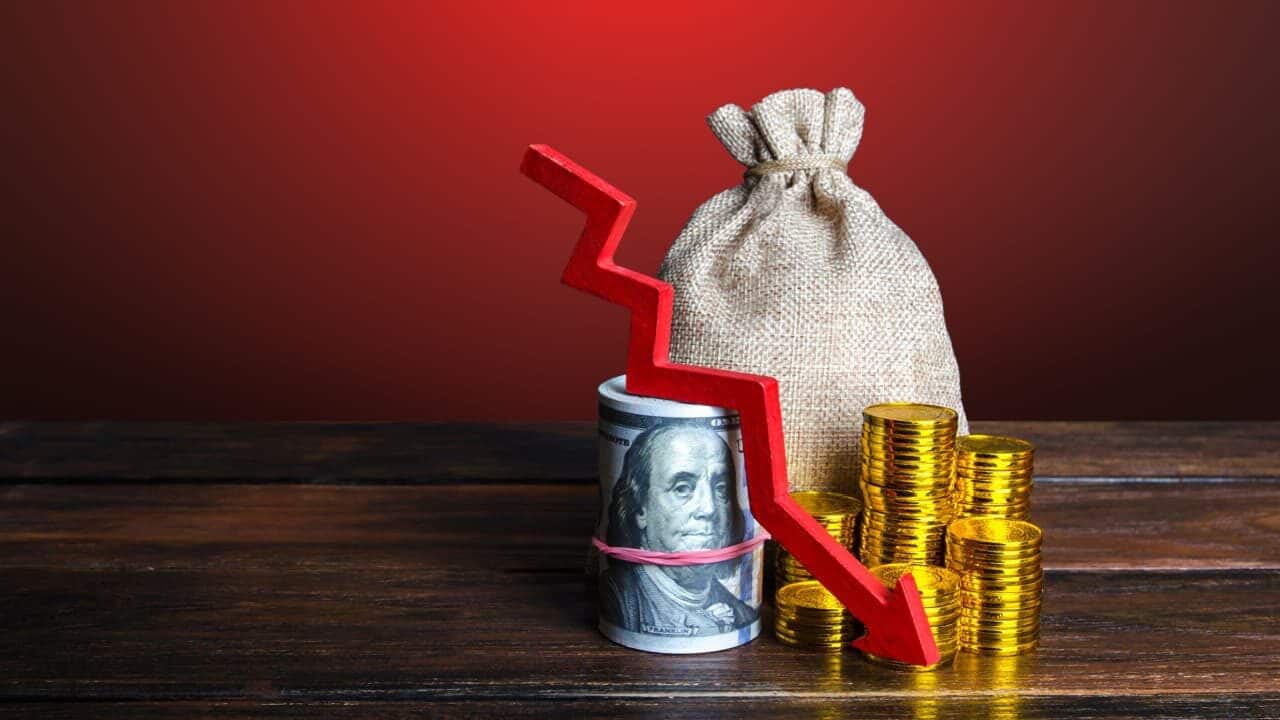 Imagem de cédulas e moedas com seta vermelha para baixo. Diminuição de fundos e dinheiro do varejo.