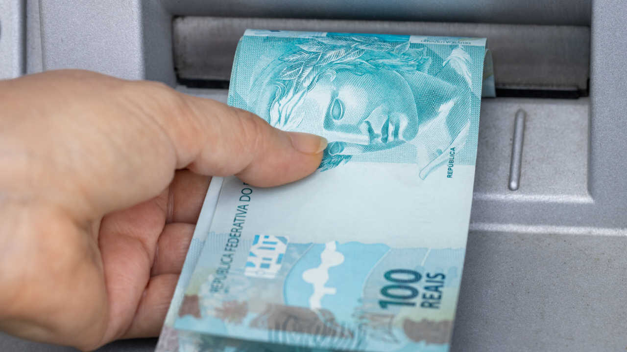notas de cem reais sendo retiradas do caixa eletrônico por uma mão para Auxílio Emergencial Saque-Emergencial