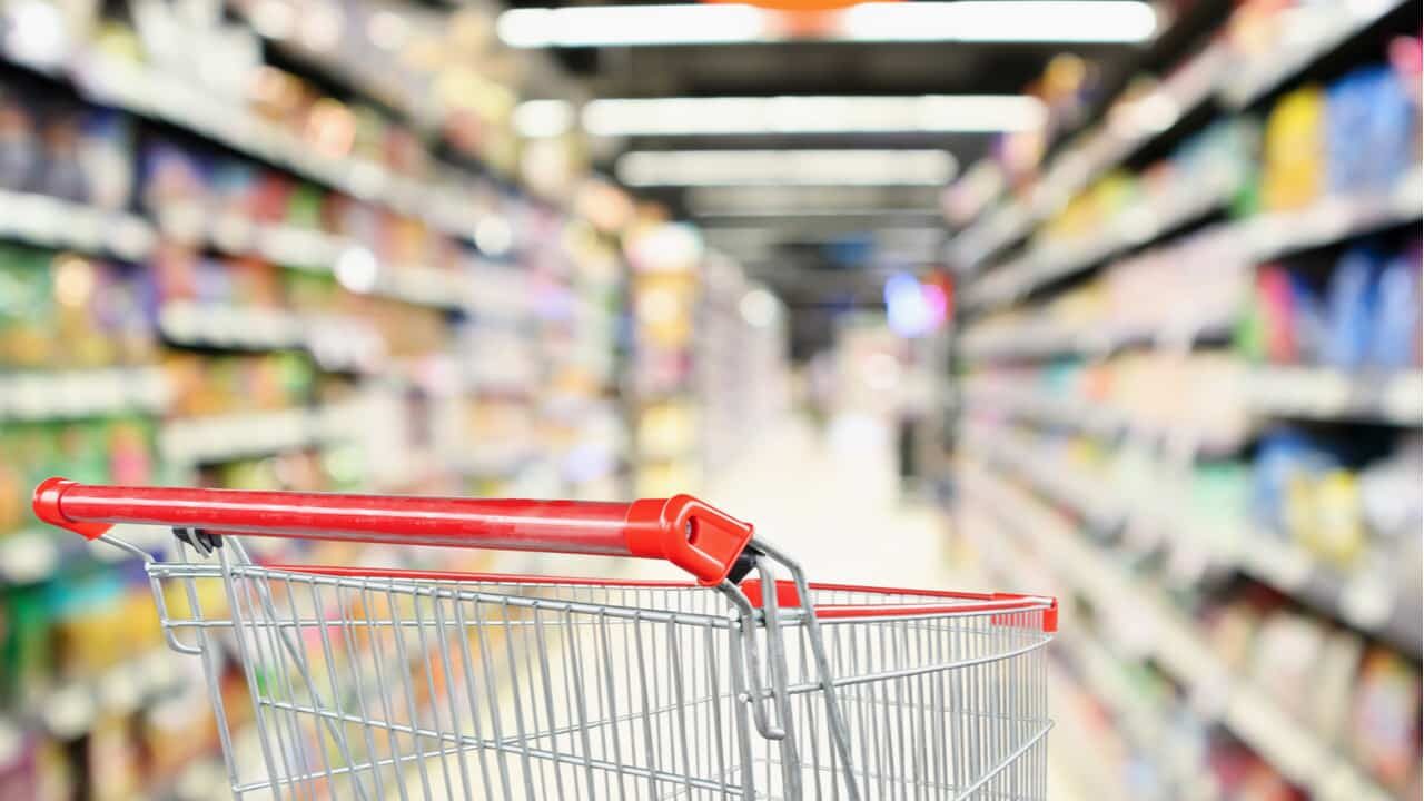 Carrinho de supermercado entre prateleiras com fundo desfocado