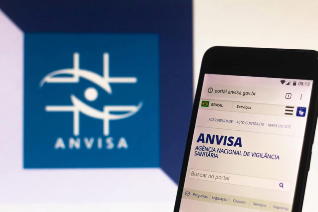 Logo Anvisa ao lado de celular com site da Anvisa aberto