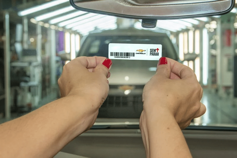Mãos femininas colocando a tag do Sem Parar no carro