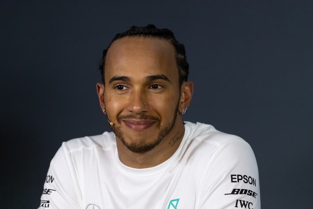 Lewis Hamilton de camisa branca em um fundo azul escuro hamburgueria