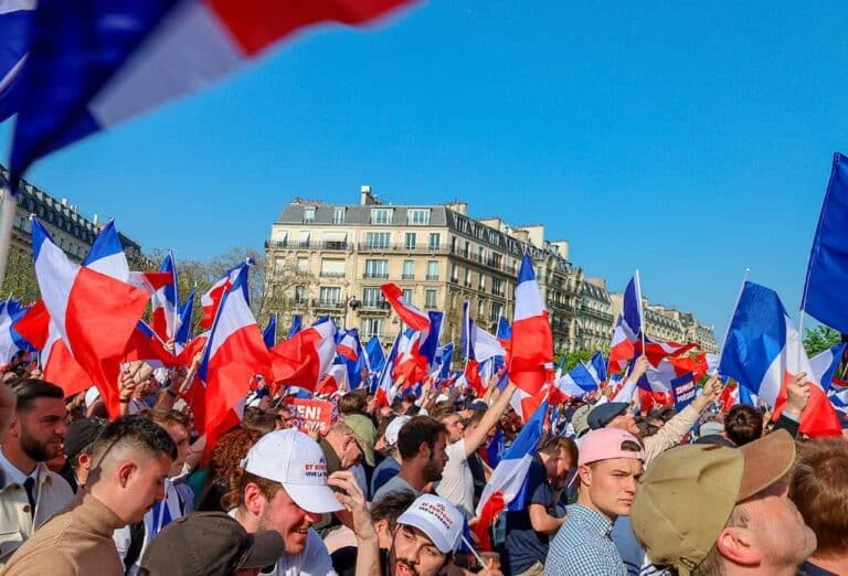 imagem de pessoas se manifestando na França contrarias à reforma da previdência, enquanto levantam bandeiras da França.