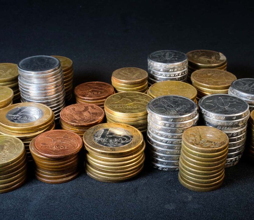 Moedas empilhadas em pilhas de 50 centavos, 25 cent. , 10 cent., 5 cent. e um real.