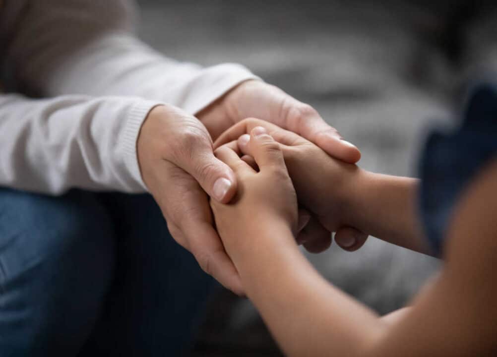 Pessoa segurando as mãos de uma criança guarda compartilhada