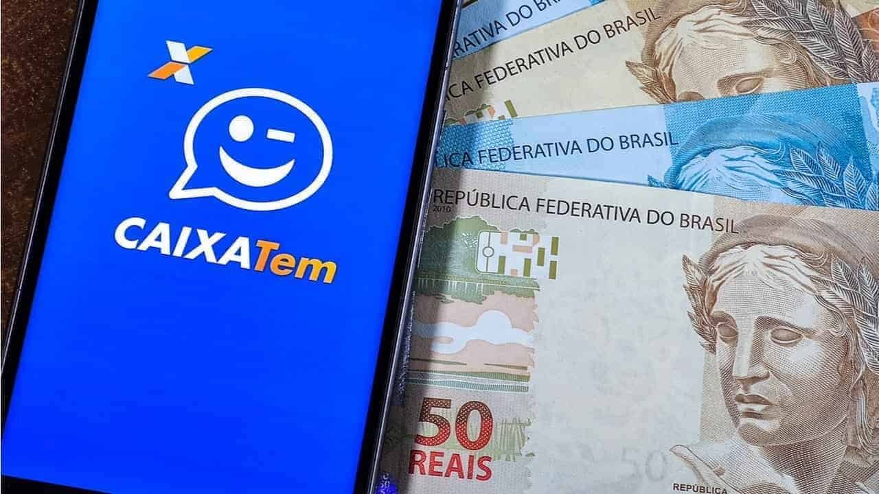 Ao lado de notas de real, celular exibe tela inicial do Caixa Tem