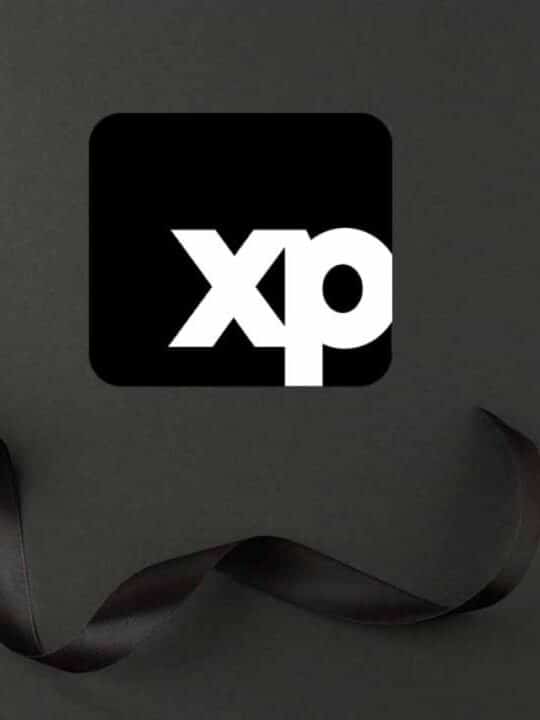 Caixa de presente com laço preto de fita. Ao lado uma logo da empresa de investimentos XP