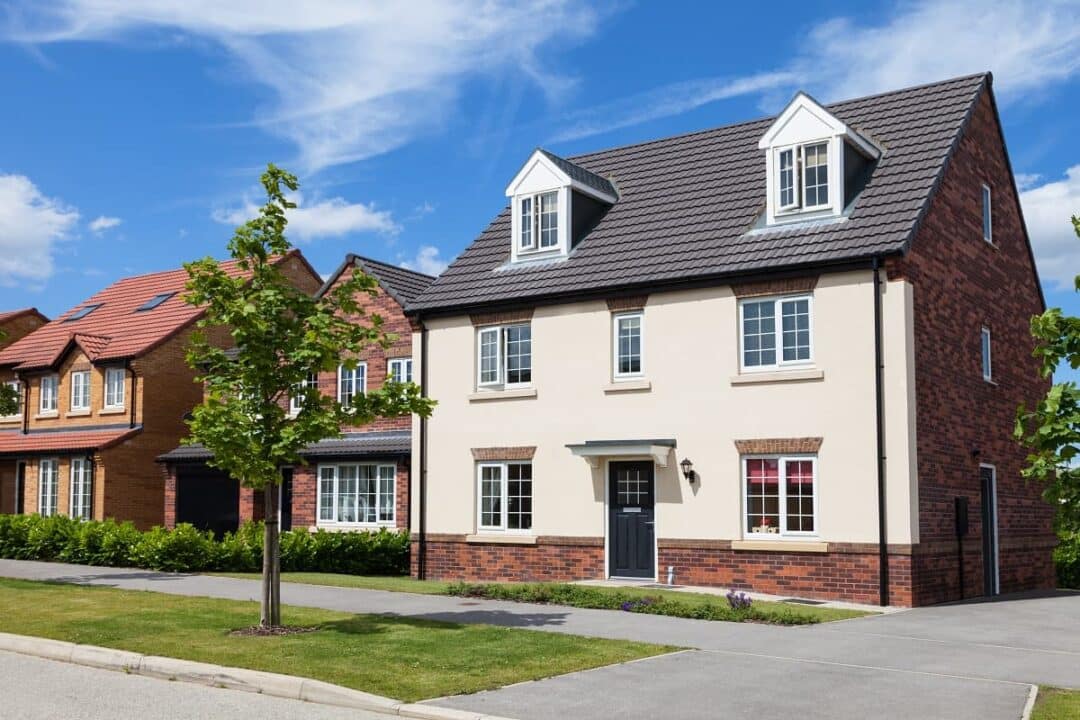 imagem de uma casa branca com janelas, à frente, uma árvore