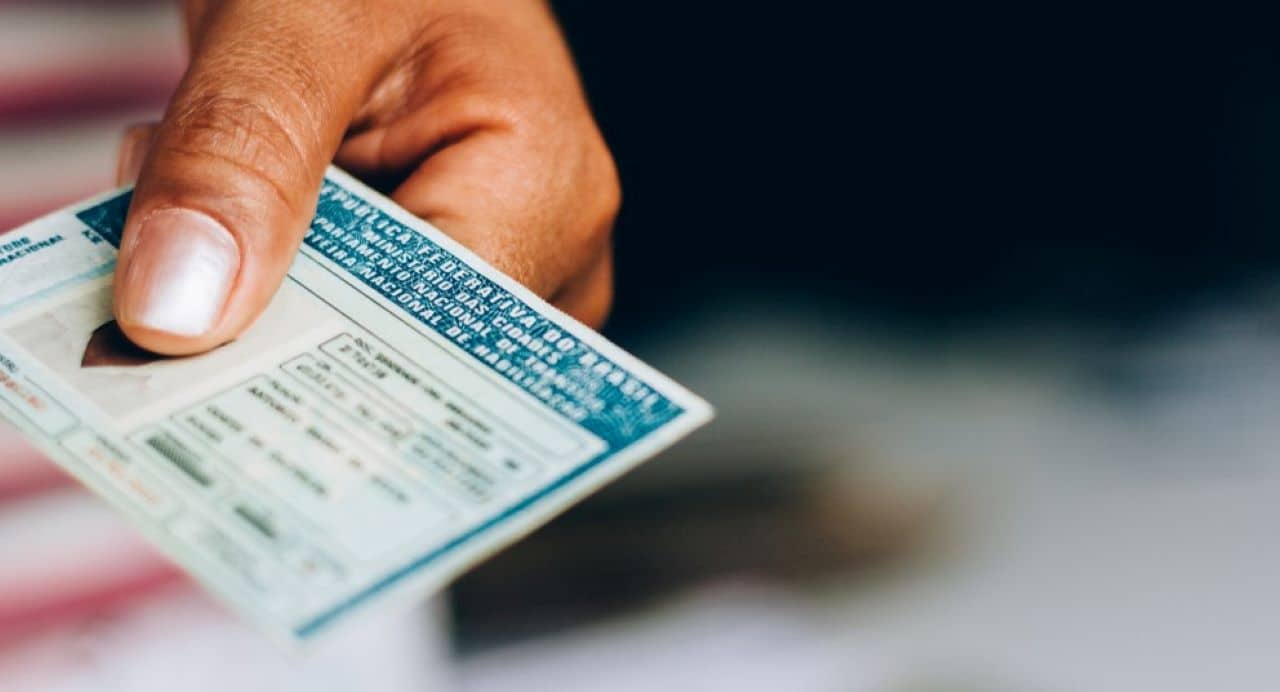 Mão feminina segurando uma carteira nacional de habilitação