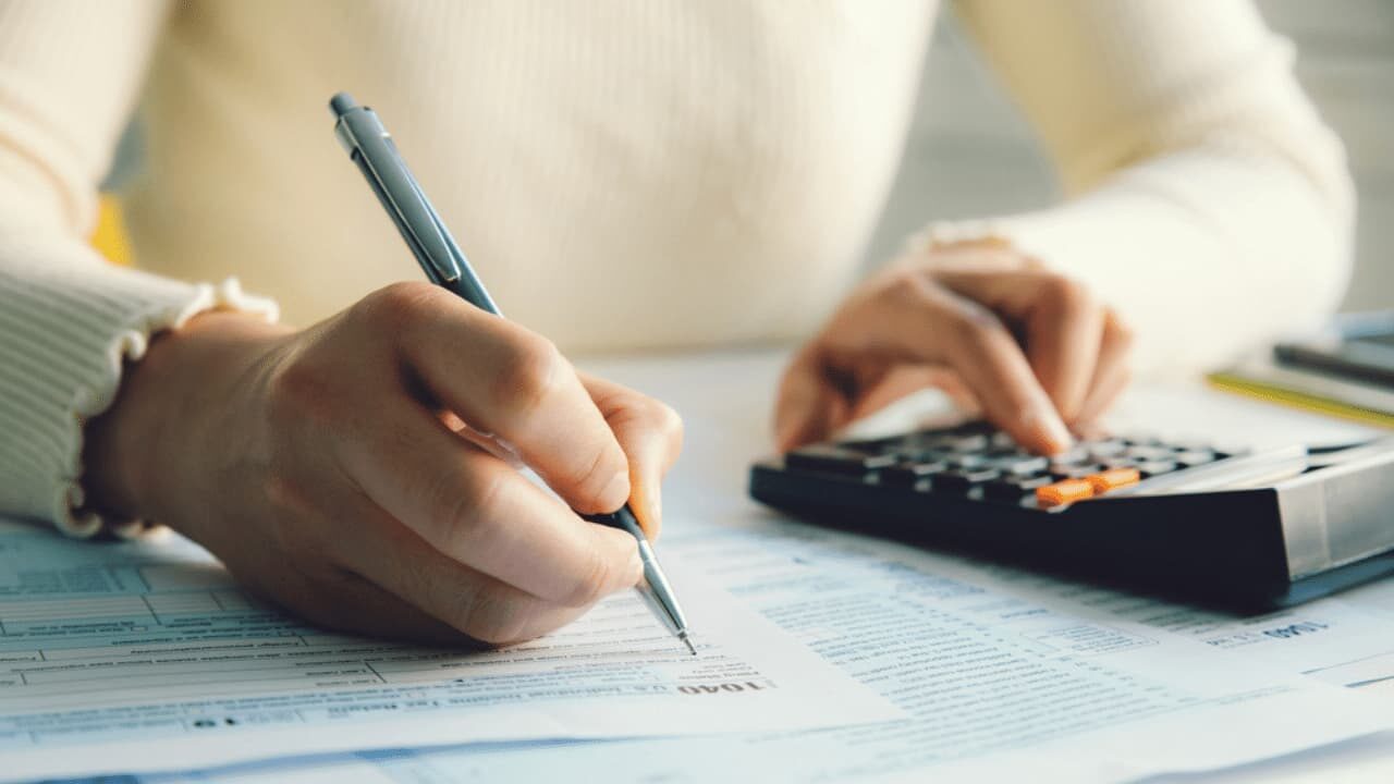 mulher calculando margem consignável com calculadora, caneta e papel