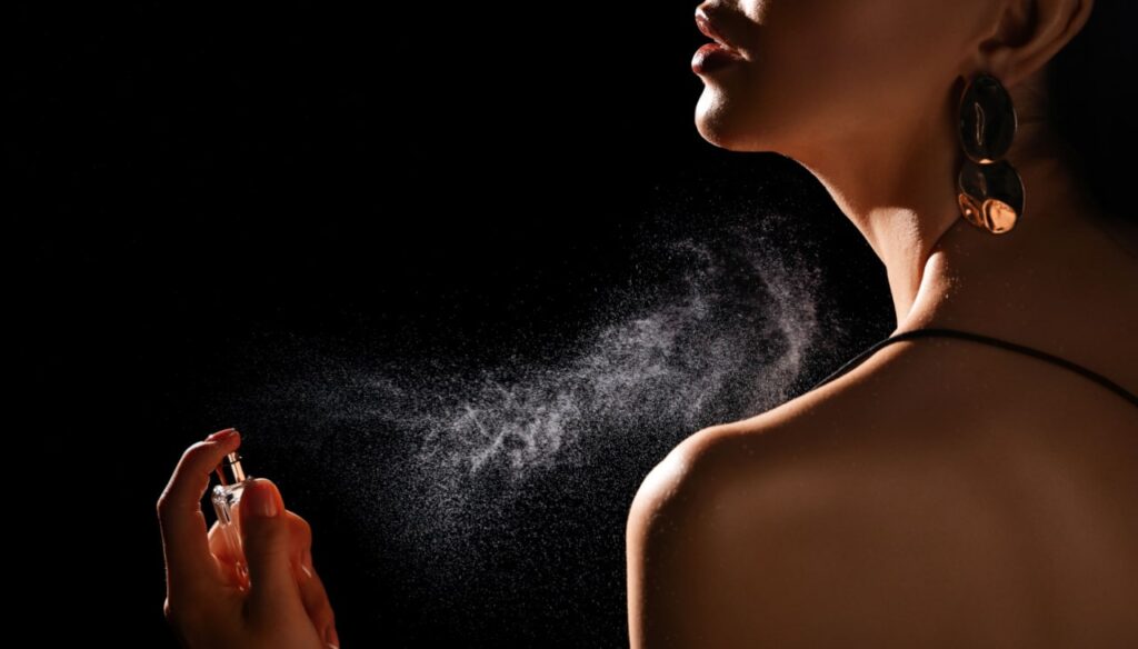 Mulher espirrando perfume em si mesma