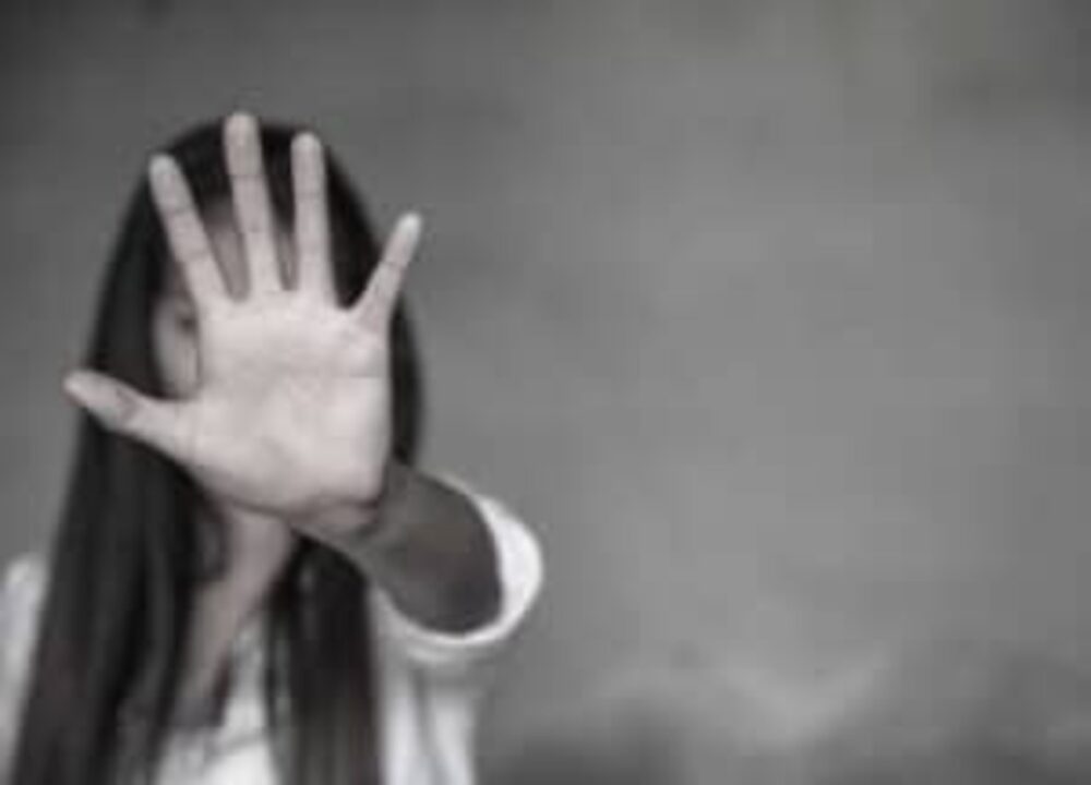 Uma mulher com a mão em frente ao rosto para impedir violência contra as mulheres