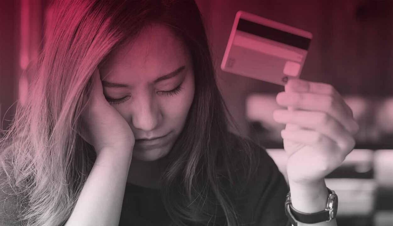 Mulher triste segurando cartão de crédito