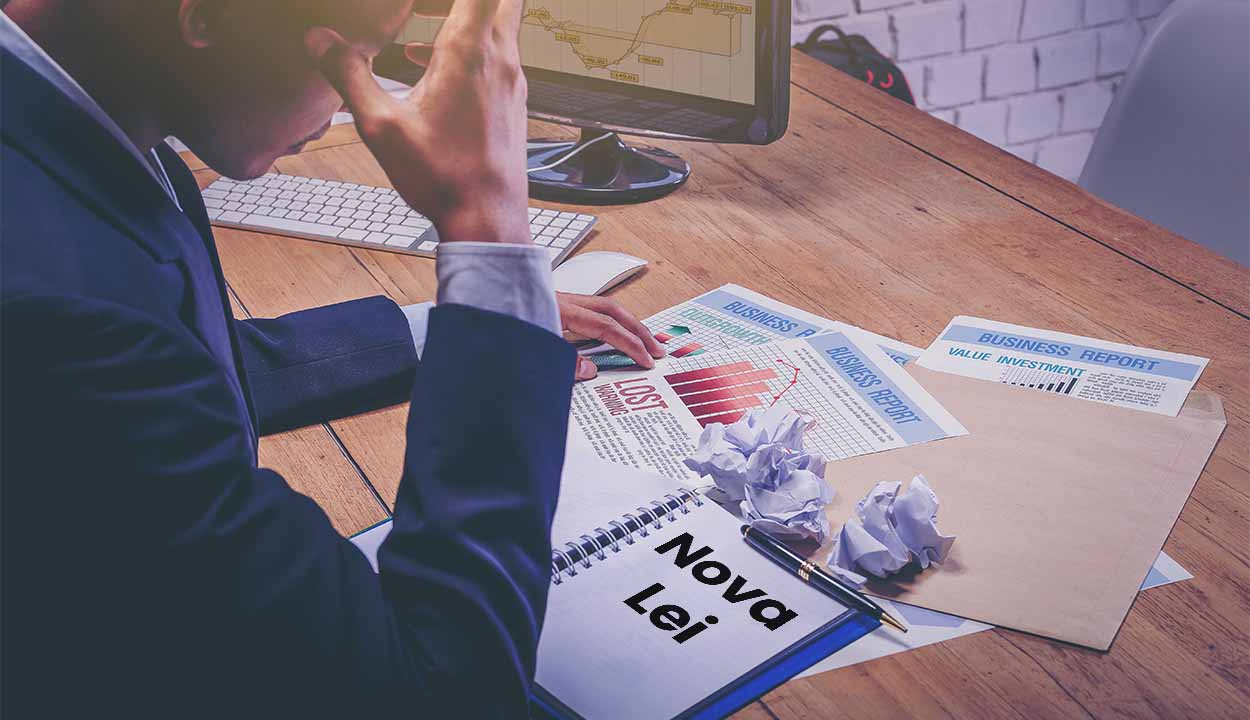 Imagem de uma empresário com a mão na cabeça enquanto lê documento sobre nova lei.