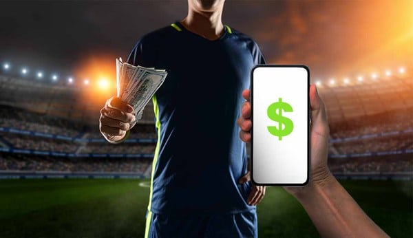 Pessoa segurando dinheiro em uma mão e um celular na outra, com a imagem de um cifrão verde em fundo branco