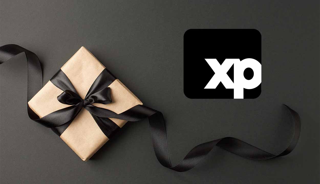 Caixa de presente com laço preto de fita. Ao lado uma logo da empresa de investimentos XP