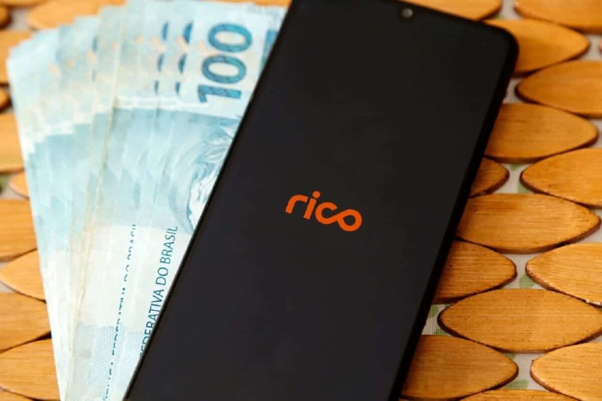 Imagem de um celular com o logo da Rico. Embaixo do aparelho, notas de R$100