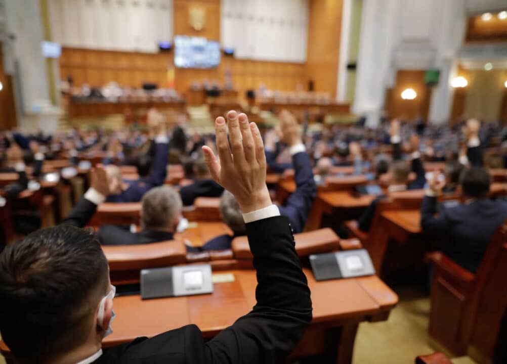 Pessoas no plenário senador com a mão levantada.