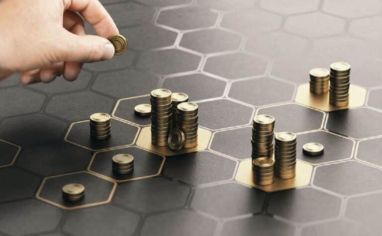 Imagem de uma mão colocando moedas em blocos.