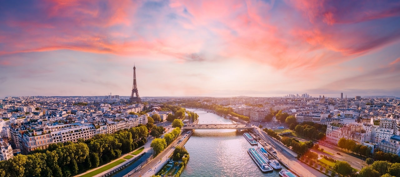 Imagem mostra uma vista panorâmica de Paris, com a Torre Eiffel no lado esquerdo e as nuvens ao fundo em tom avermelhado