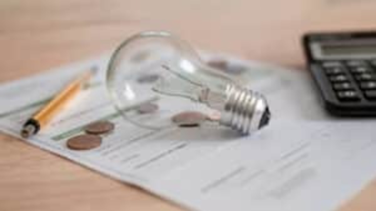 Imagem de lâmpada sobre contas de luz e moedas