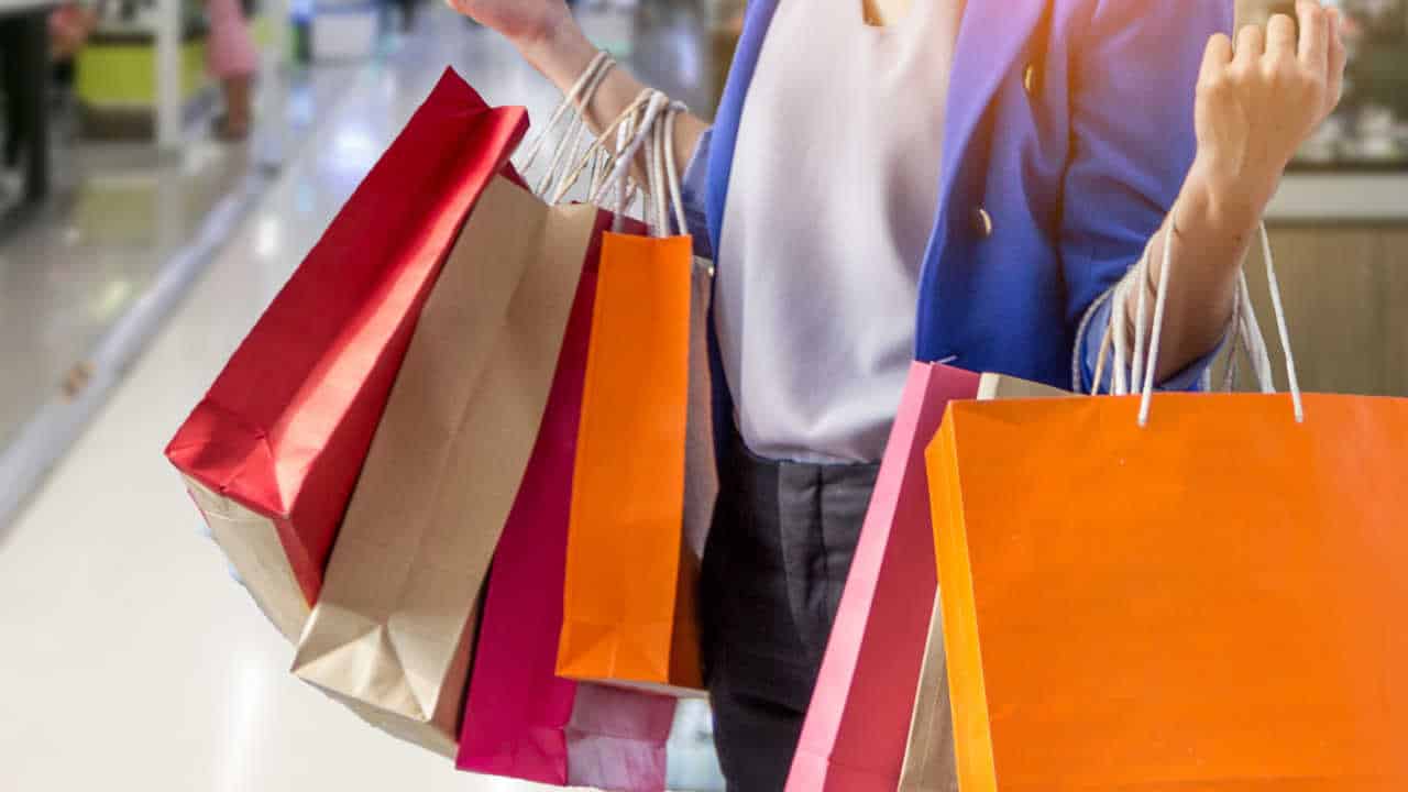mulher segurando muitas sacolas de compras