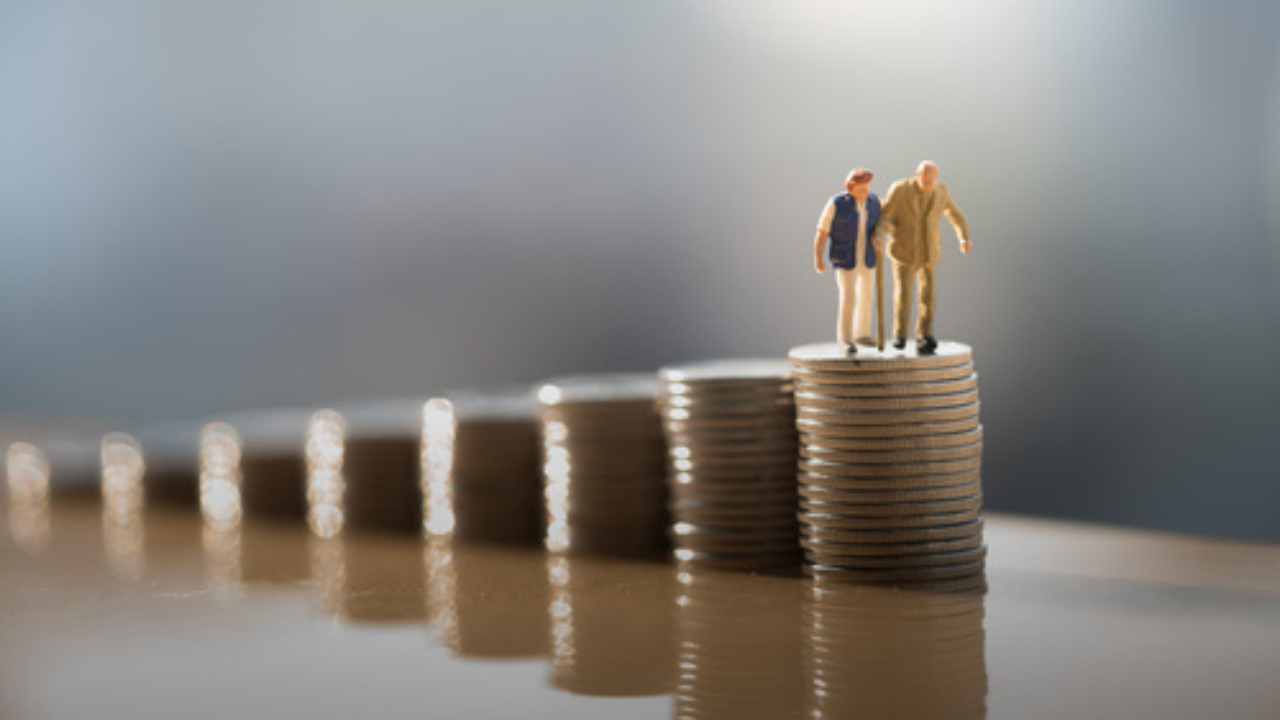 Sequência de moedas empilhadas com dois bonecos idosos em cima