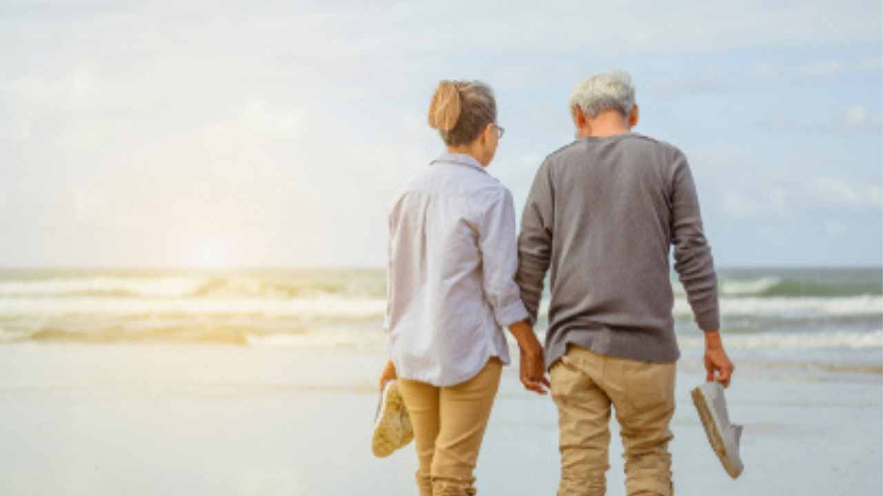 casal idoso andando de mãos dadas na praia