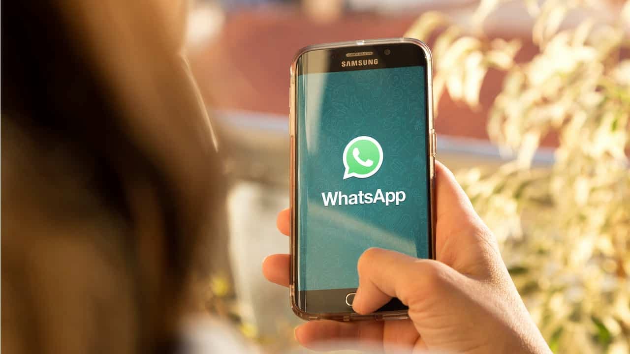 Pessoa segurando um celular com o app do WhatsApp aberto