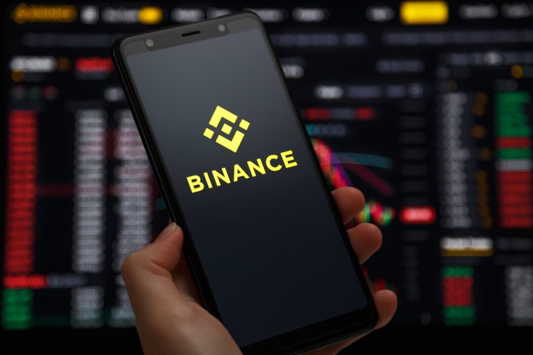 mão segurando celular com logo da Binance na tela