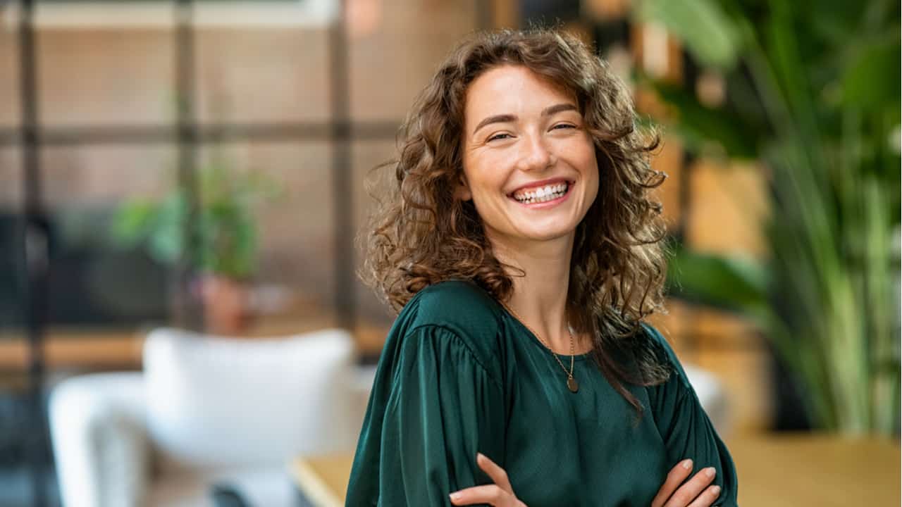 mulher de braços cruzados e postura ereta sorrindo