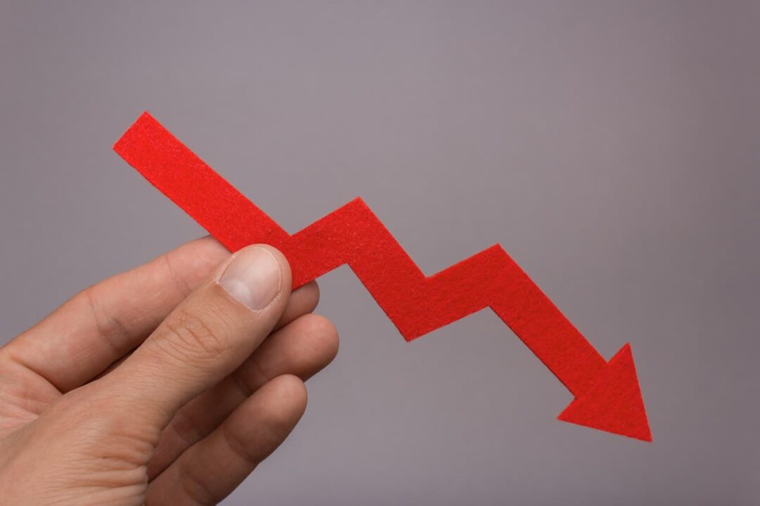Mão segurando seta vermelha em queda