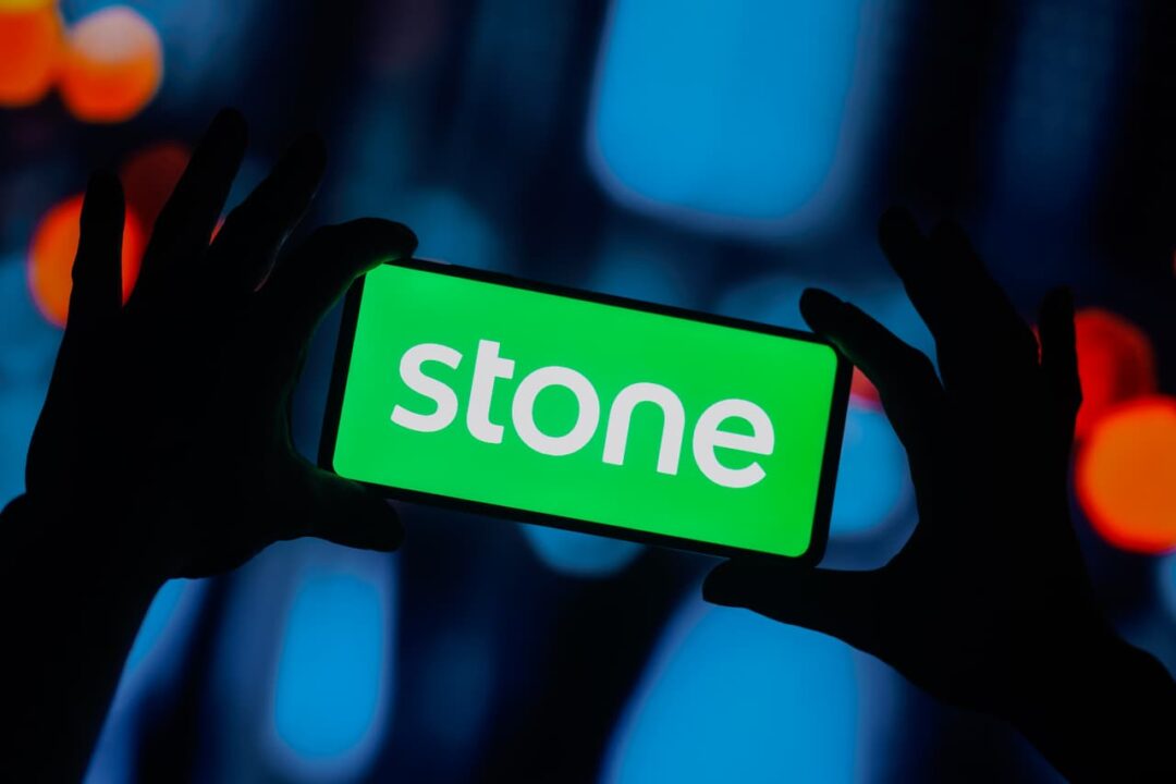 Pessoa segurando celular com logo da Stone