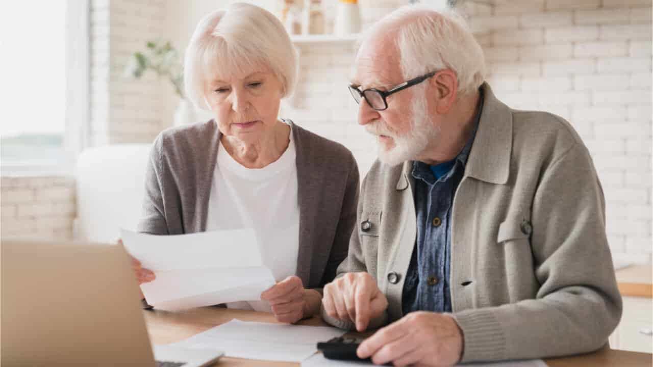 casal de idosos calculando documento de aposentadoria por invalidez