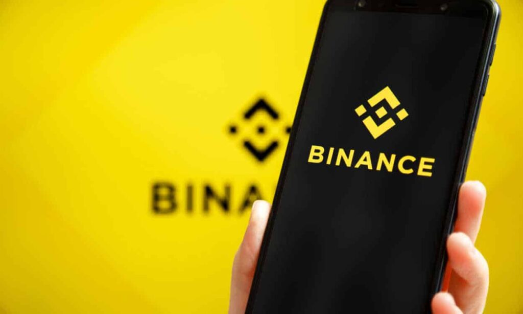 Pessoa segurando um celular com a logo da Binance na tela