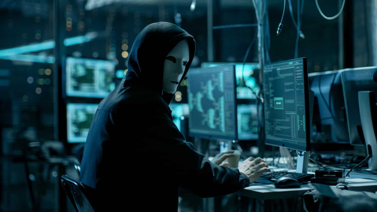 pessoa mascarada mexendo em computador