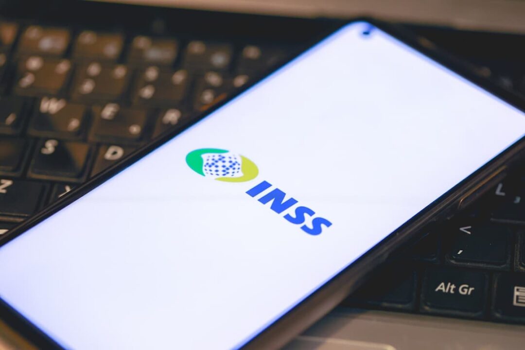 Imagem de um celular com o aplicativo do INSS aberto, em cima de um teclado.