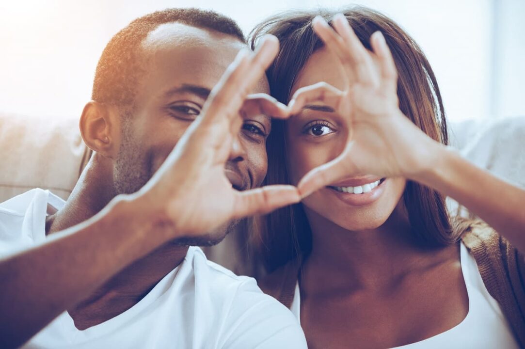 Casal de jovens negros fazendo coração com suas mãos