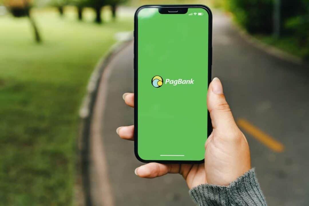 Pessoa segurando celular que mostra tela inicial do aplicativo PagBank