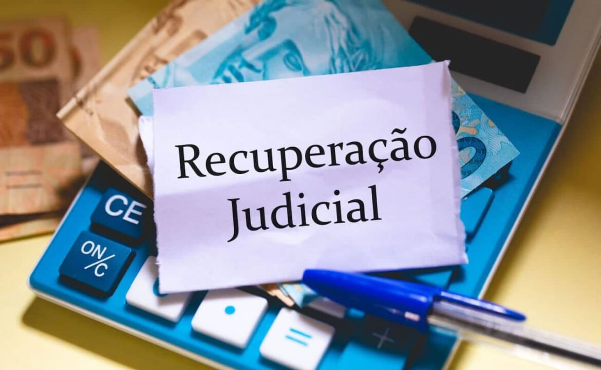 Notas de Real em cima de uma calculadora com um papel escrito Recuperação Judicial no topo.