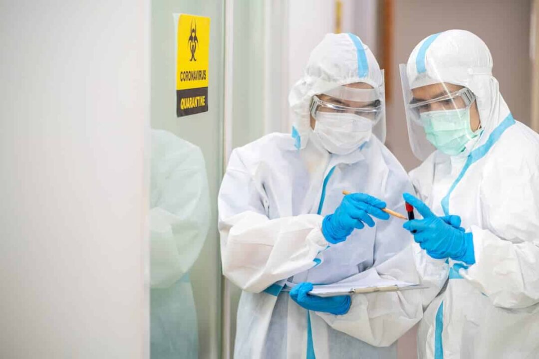 Técnicos com EPIs de segurança contra Coronavirus durante análise laboratorial