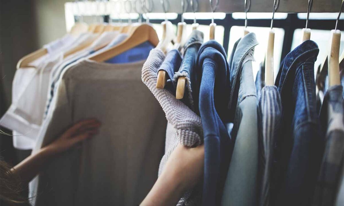 uma pessoa arrumando uma arara de loja de roupas
