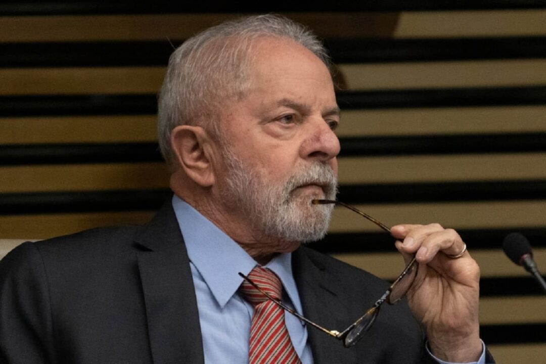 Imagem de Lula olhando para o lado com a haste de um óculos levada à boca