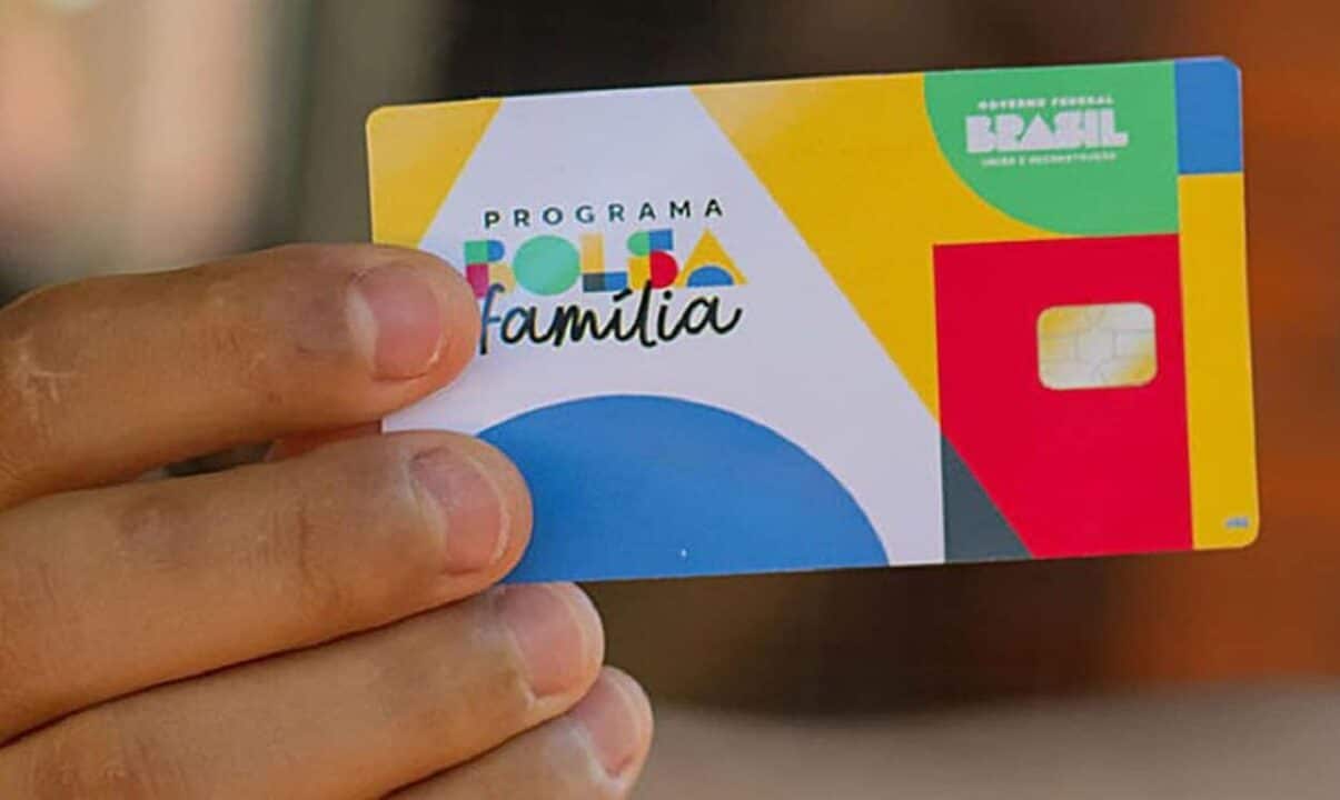Mão segurando um cartão do Bolsa Família
