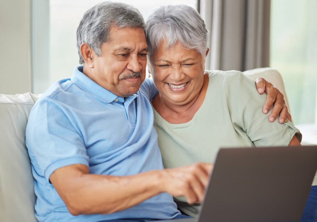 Casal idoso feliz enquanto mexe em computador